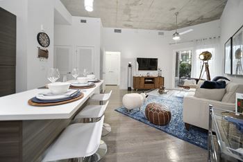 a living room and dining room with a white table and white chairs and a blue rug at Altis Grand Central, Tampa, FL